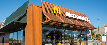 Clădirea Mcdonalds cu cer albastru și logo în fața clădirii