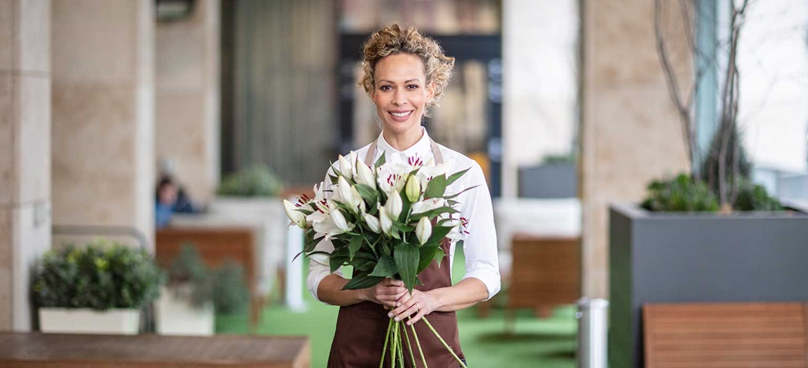 Florar care deține o grămadă de crini, plante, masă, scaune în aer liber