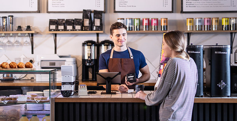 Barista într-o cafenea care servește mai multe femei