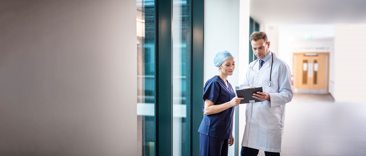 Doctor cu stetoscop la gât discutând cu doctoriță pe coridor