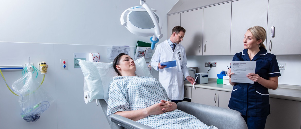 Pacientă la tratament cu doctor și asistentă completând un formular